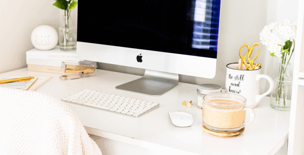 Photo of a work desk with a computer, cup of coffee and other decors.