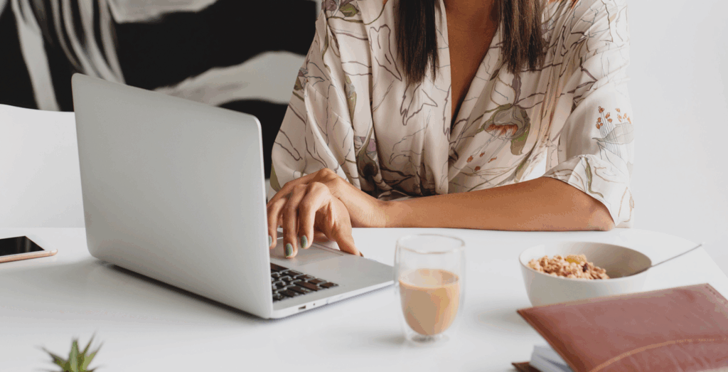 Person working on a laptop at a desk with coffee and a notebook, representing a success mindset and a calm, intentional approach to work and growth.