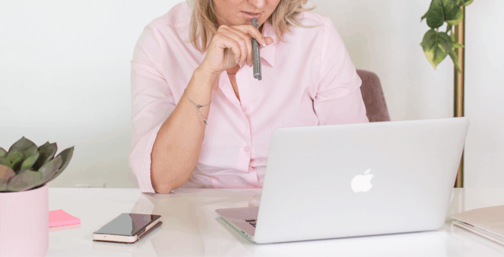 Entrepreneur sitting at a laptop deep in thought, highlighting the pressure of traditional productivity culture and the importance of redefining productivity for solopreneurs who want to stop feeling unproductive while building healthier, burnout-free work habits.