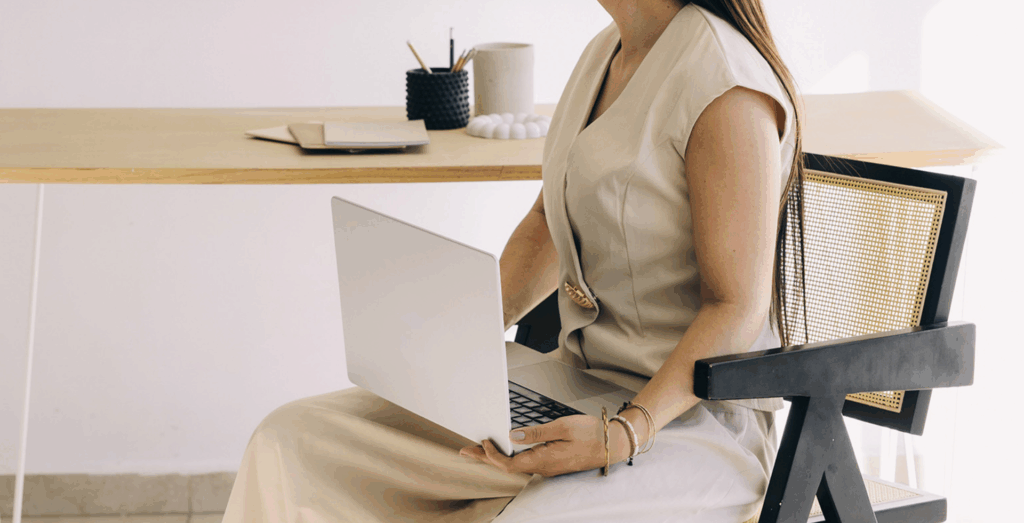 Female entrepreneur working on a laptop in a minimalist office, illustrating why I keep putting off systems and the fear of making mistakes while learning to create systems before you're ready instead of waiting to build systems.