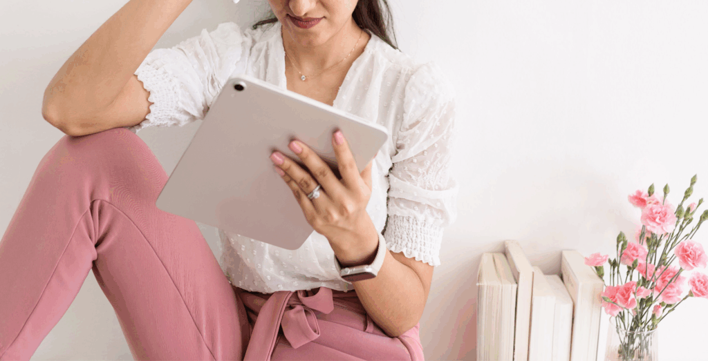 Female solopreneur using a tablet while sitting indoors, illustrating productivity for solopreneurs and redefining productivity through intentional work habits, sustainable success, and productivity without burnout instead of constantly feeling overwhelmed or unproductive.