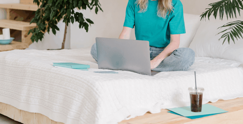 Solopreneur working comfortably from bed on a laptop, showcasing a healthier approach to productivity without burnout and redefining productivity through flexible routines, intentional work, and realistic daily habits that prevent feeling constantly unproductive.