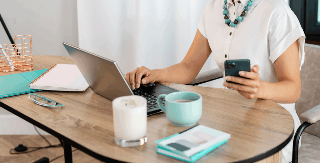 Solopreneur working at a desk with a laptop and smartphone, representing modern productivity strategies, redefining productivity through balance and focus, and helping entrepreneurs stop feeling unproductive by creating sustainable routines that support productivity without burnout.